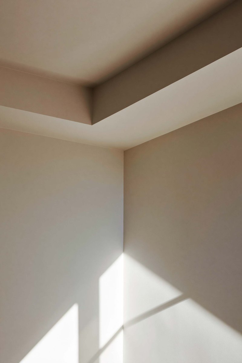 Plain finished wall in an empty room with daylight from tall windows